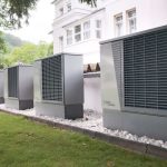 Row of heat pumps outside a building promoting sustainable energy solutions.