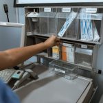A healthcare worker organizes medical supplies in a clinic room, focusing on efficient storage.