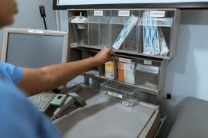 A healthcare worker organizes medical supplies in a clinic room, focusing on efficient storage.
