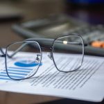 Eyeglasses on financial report with calculator in office setting, highlighting analysis.