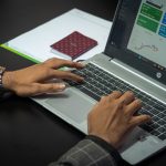 Close-up of hands on a laptop keyboard with a business dashboard on screen, ideal for finance or tech themes.